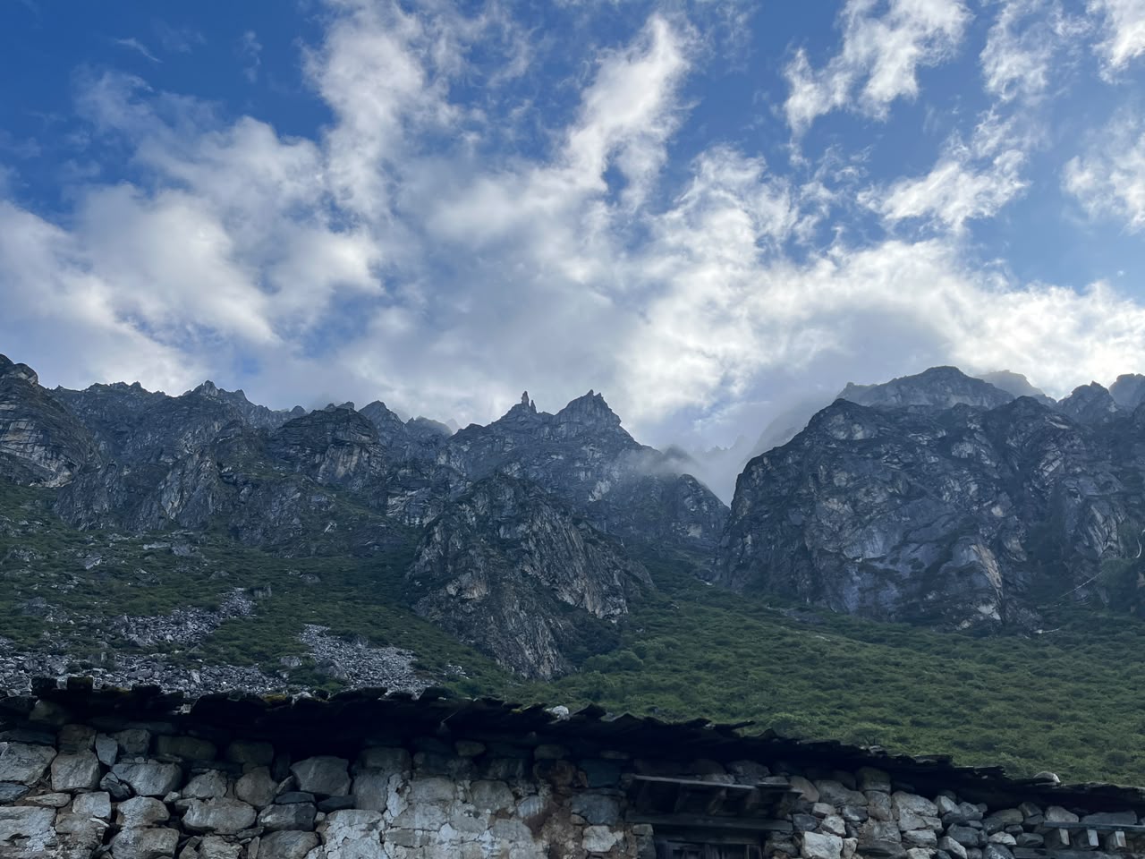 Jagged peaks above Lapche, seen past a stone hut roof
