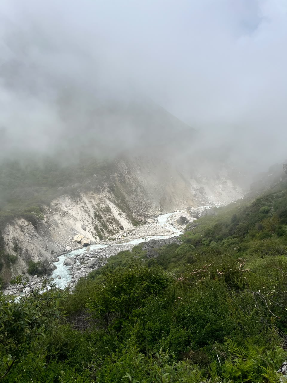 Cloud rolling into a misty gorge with a glacial river below