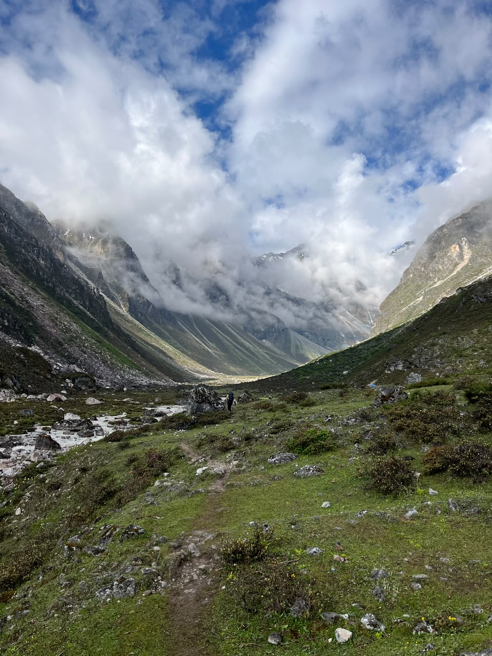 The trail descending toward the river, clouds rolling through the valley below